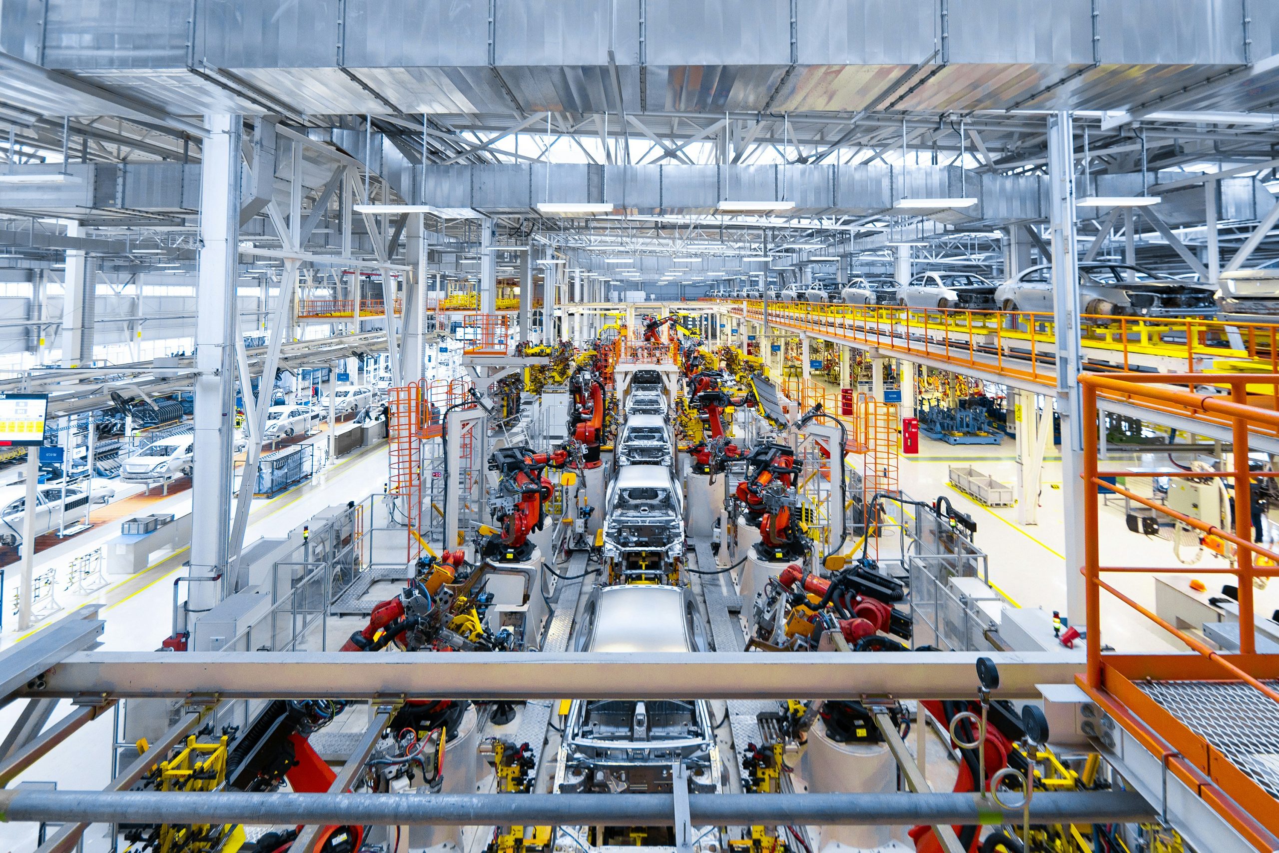 A large-scale automotive production line filled with coordinated robotic systems assembling vehicle bodies—illustrating the type of high-volume, precision-driven operations that Nvexus helps improve through automated planning, material flow visibility, and real-time data accuracy.