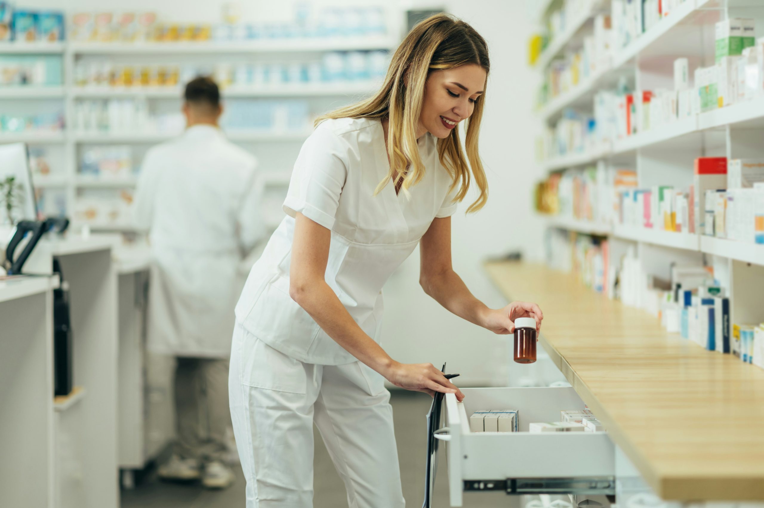A pharmacist manages prescription inventory by retrieving medication from a drawer—illustrating the accuracy, traceability, and stock-control challenges that Nvexus helps healthcare organizations manage across regulated supply chains.
