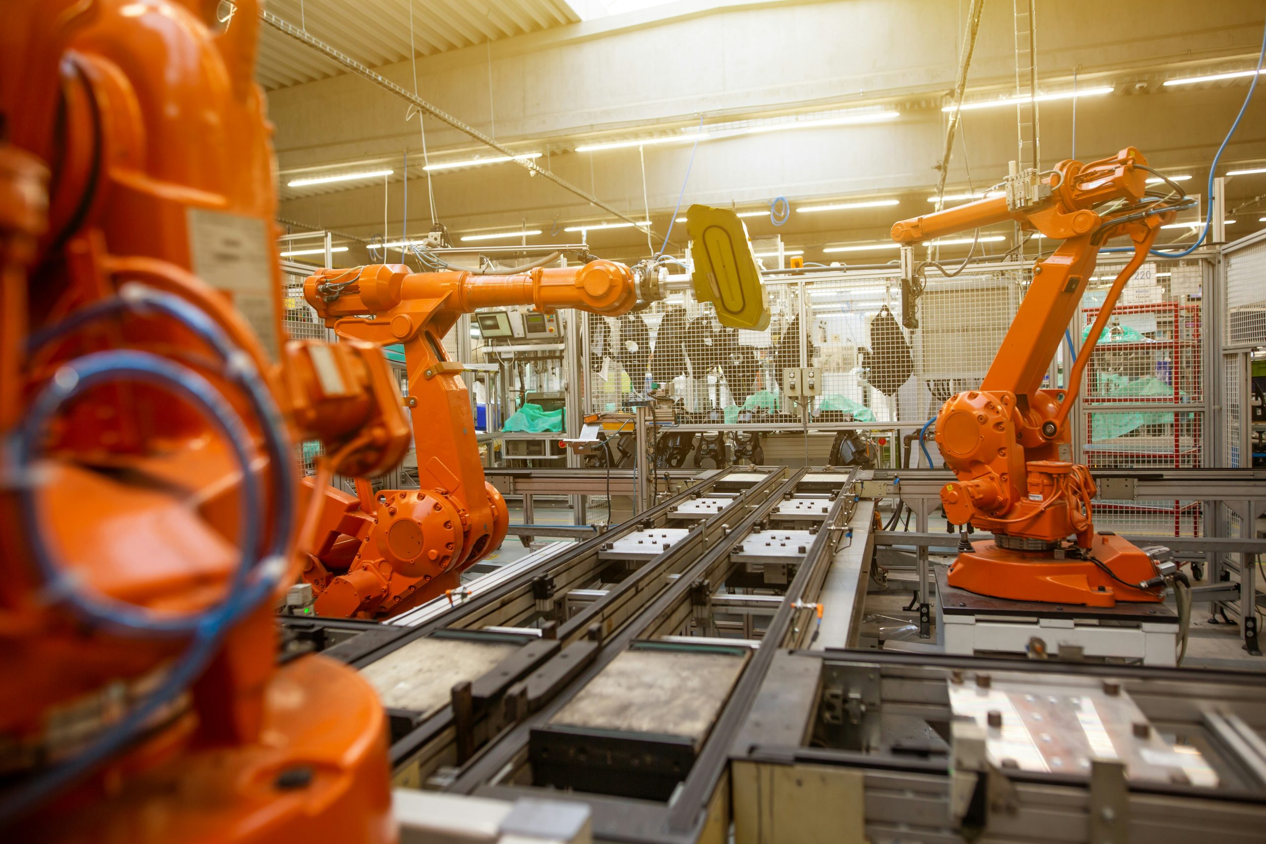 Automated robotic arms performing material handling tasks on a multi-lane conveyor system inside a modern factory, illustrating advanced manufacturing automation and industrial robotics.