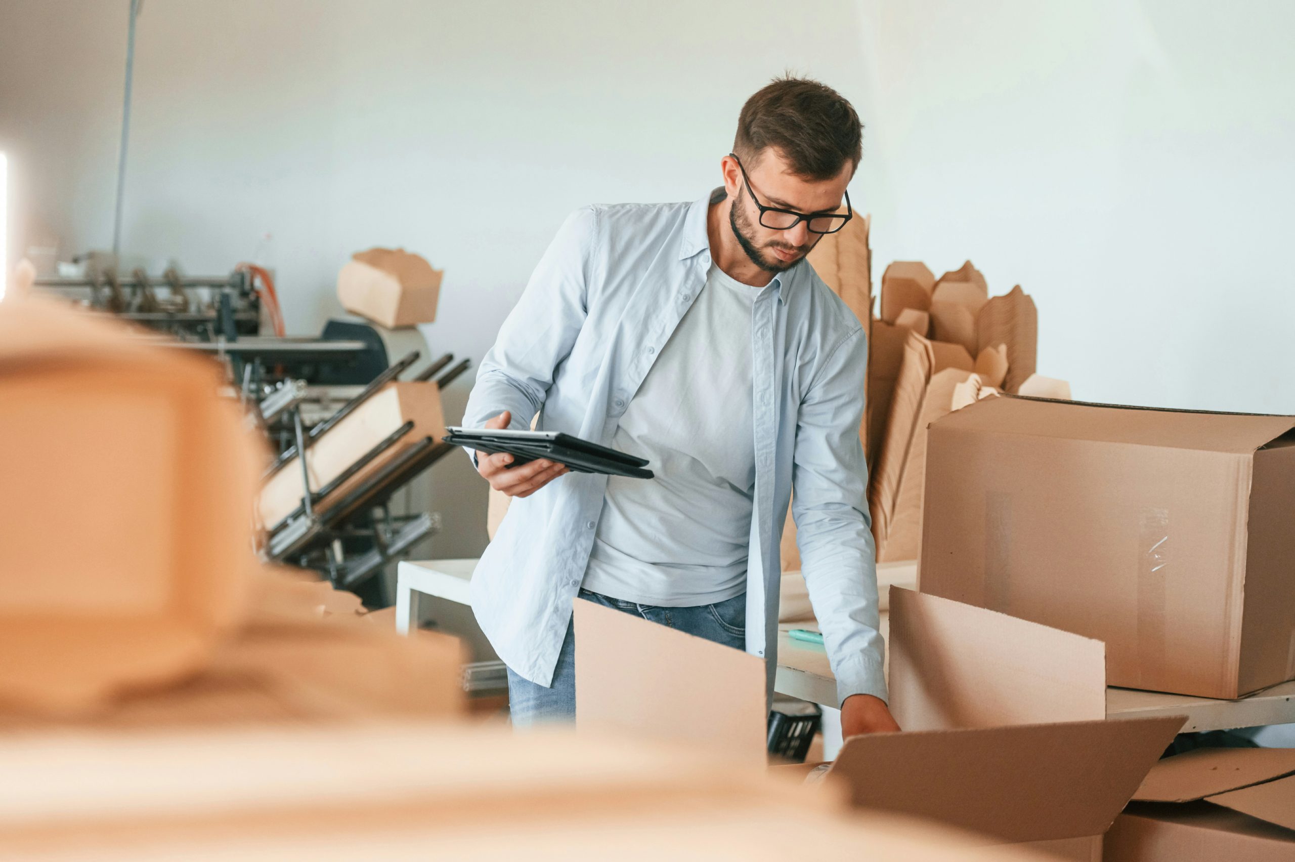 A small business operator checks packaging and inventory using a tablet—illustrating the manual workflows and order accuracy challenges that Nvexus helps streamline through automated planning and visibility.