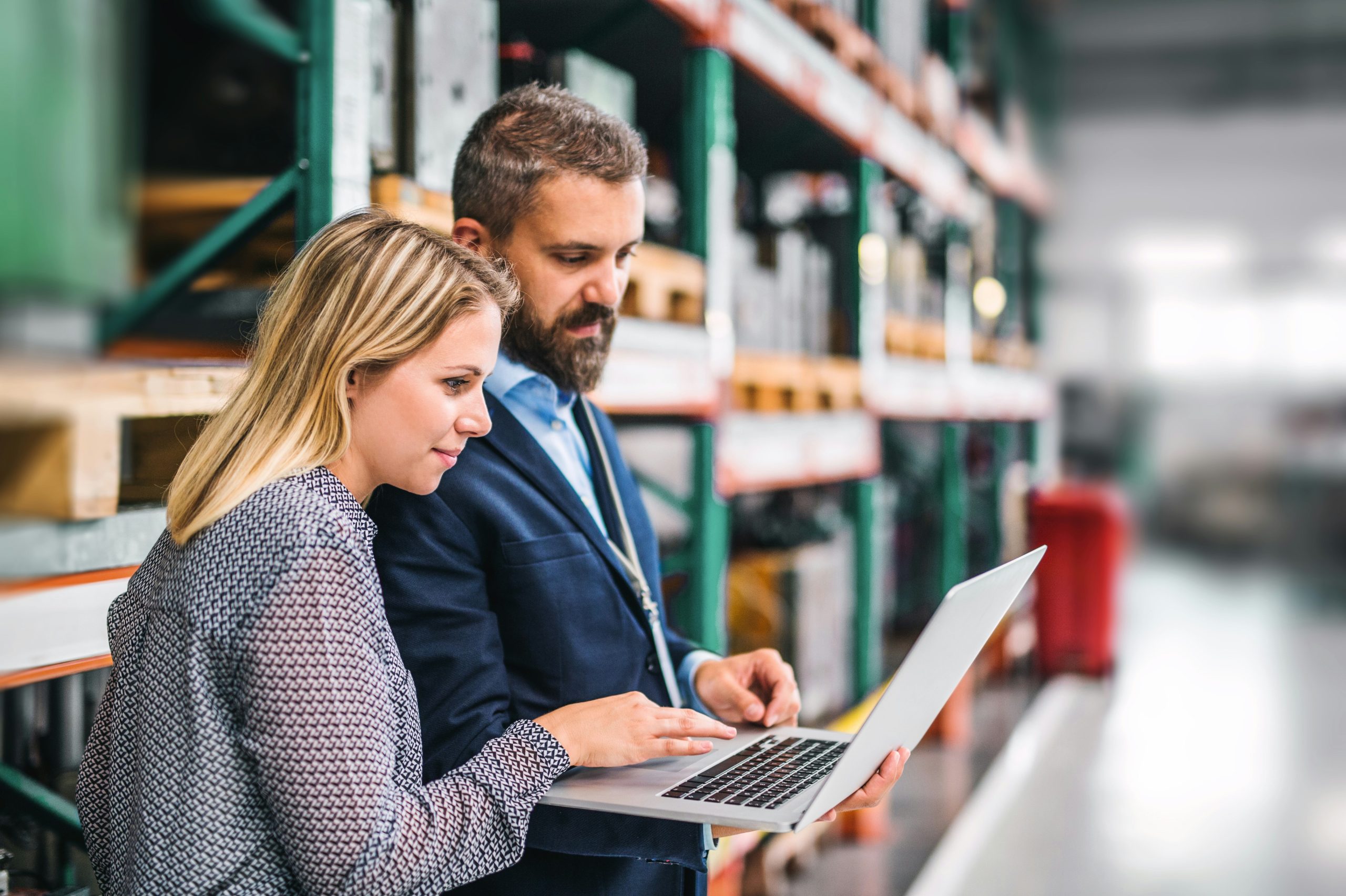 Small business team analyzing inventory and planning data using a laptop in a warehouse.
