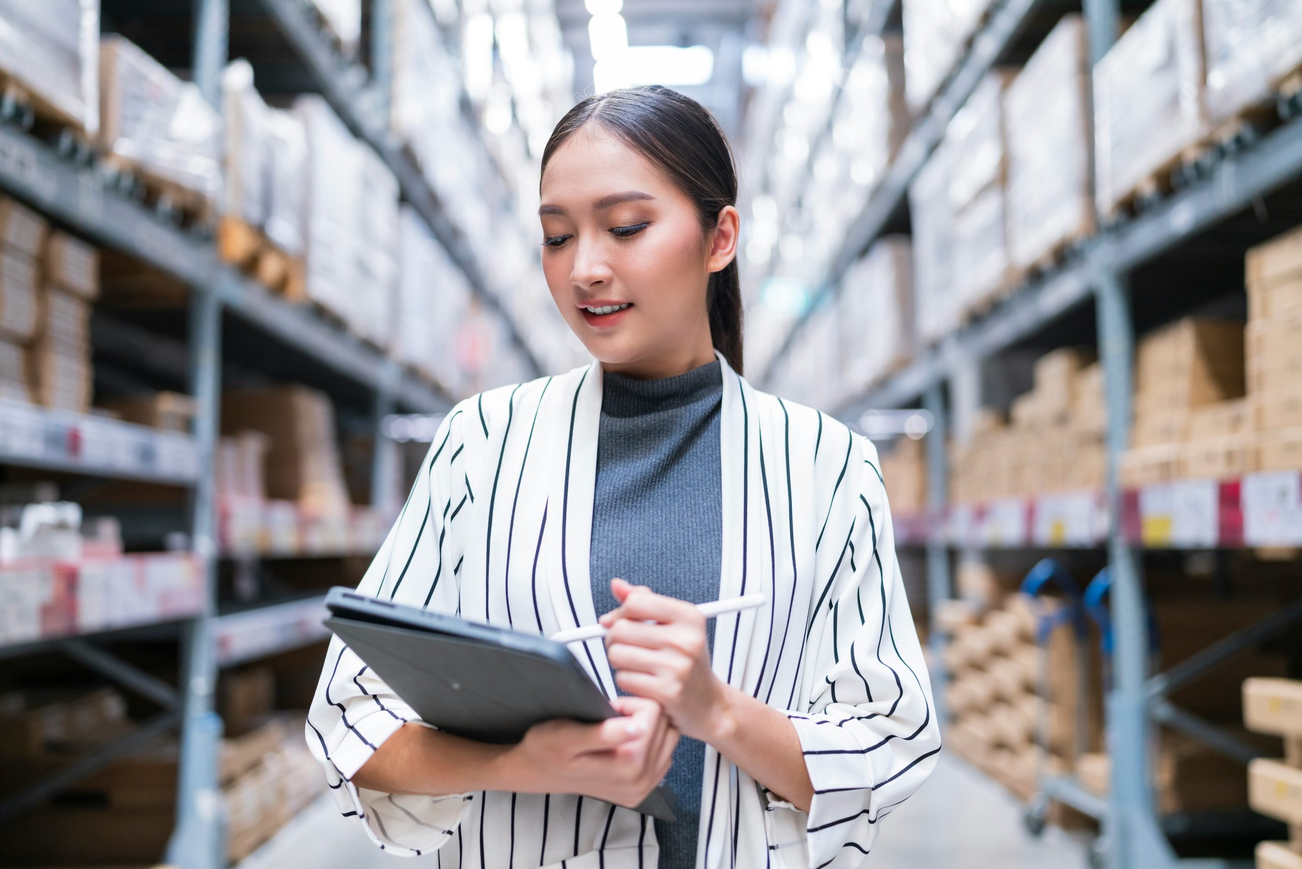 Supply chain professional analyzing inventory and planning data on a tablet in a warehouse environment, representing real-time execution visibility.